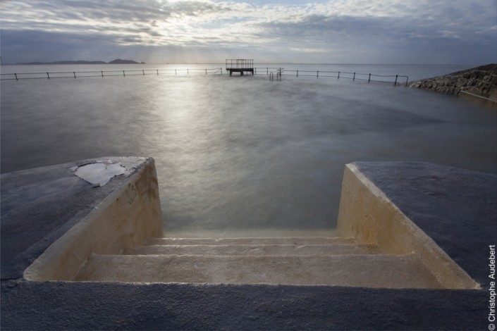 Marches descendant dans une piscine d'eau de mer avec vue sur un plongeoir, à Guernesey, Royaume Uni. Prise de vue en pose longue.